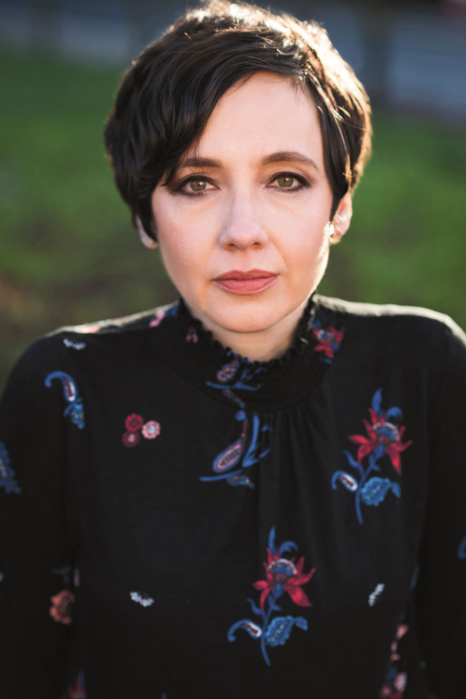 Portrait photo of Ilona Bannister '07 with a deadpan face and short hair with a black floral top